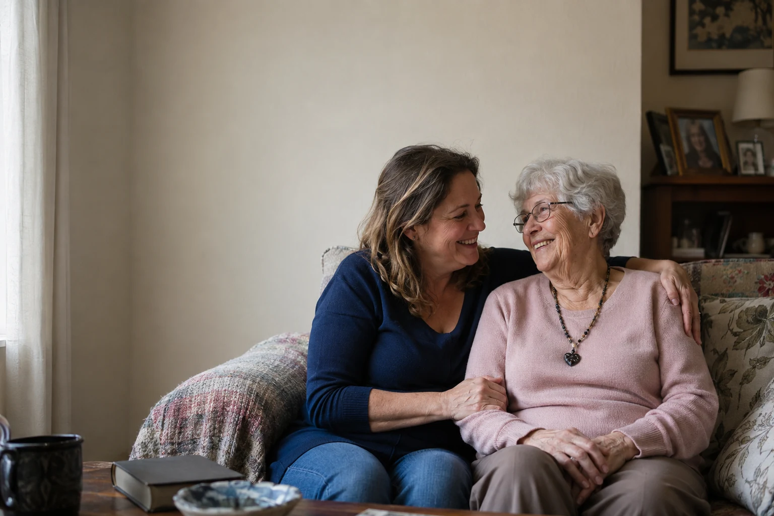 An adult daughter embracing her mother in their sunny living room